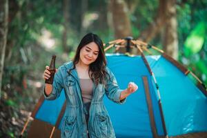 jeune femme applaudir et boire une boisson devant la tente de camping photo