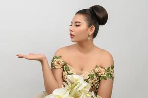 Jeune belle mariée asiatique avec bouquet d'orchidées sur fond blanc photo