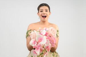 Jeune belle mariée asiatique avec bouquet d'orchidées sur fond blanc photo