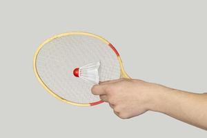 homme main en portant une badminton raquette sur gris Contexte. photo