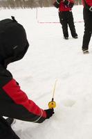 méconnaissable la personne en portant une Plastique la glace pêche barre sur un glacé lac. photo