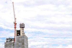 grues de levage travaillant à la construction de bâtiments sur un ciel bleu vif et un grand fond de nuage. photo