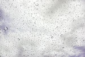 fermer gouttes de pluie sur verre et floue il pleut des nuages Contexte. photo