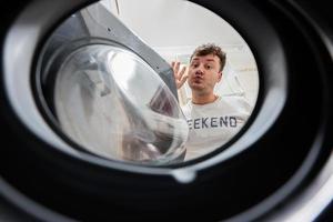 homme vue de la lessive machine à l'intérieur. Masculin Est-ce que blanchisserie du quotidien routine. baiser toi. photo