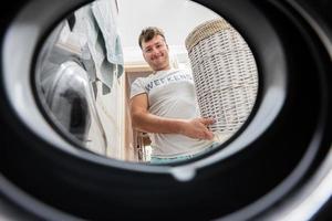 homme avec panier, vue de la lessive machine à l'intérieur. Masculin Est-ce que blanchisserie du quotidien routine. photo