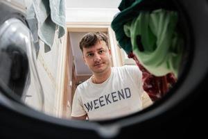 homme vue de la lessive machine à l'intérieur. Masculin Est-ce que blanchisserie du quotidien routine. photo