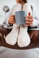 Cropped shot of woman sitting holding a mug à pieds photo