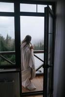 femme buvant du thé sur le balcon confortable d'une maison de campagne. photo