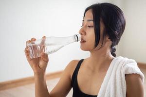 femme en buvant Plastique l'eau bouteille dans main après exercer. photo