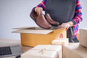 en ligne les vendeurs sont emballage des chaussures dans une boîte à livrer des produits à le acheteurs commandé sur le site Internet. petit pme affaires photo