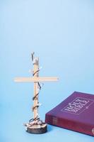 croix décorée de fleurs avec la sainte bible sur fond bleu. concept minimaliste de vacances de pâques photo