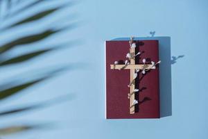 croix décorée de fleurs avec la sainte bible sur fond bleu. concept minimaliste de vacances de pâques photo