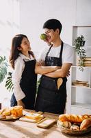 dans cuisine à la perfection content couple en train de préparer en bonne santé nourriture, beaucoup de des légumes. homme jongle avec des fruits, fait du sa petite amie rire. charmant gens dans l'amour avoir amusement photo