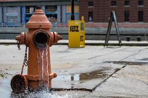 bouche d'incendie orange de la rue répandant de l'eau dans la rue photo