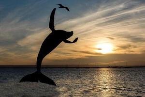 silhouette à bosse baleine briser statue à le coucher du soleil photo