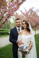 jeunes mariés marcher dans le parc parmi Cerise fleurs photo