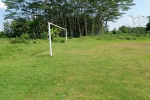 le poteau de but sur le football champ dans une village entre des arbres et jardins photo