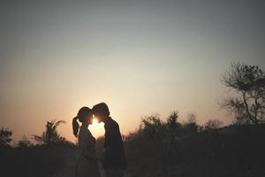 le silhouette couple pour avant mariage, avec une magnifique le coucher du soleil vue et silhouette de colline Contexte avec arbre et herbe photo