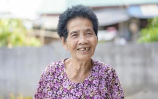 fermer de vieux asiatique femme visage avec les rides personnes âgées senior. souriant bonheur avec une peu cassé les dents à la recherche à le caméra. Sénior femme en bonne santé a positif pensées sur vie. soins de santé concept photo