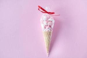 coloré brillant meringues dans gaufre biscuits dans une paquet mensonge sur une rose Contexte photo