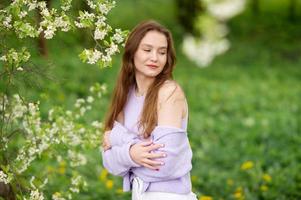 une Jeune fille dans une chandail suivant à blanc fleurs sur une arbre photo