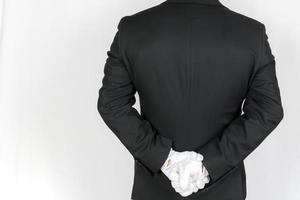 portrait d'un majordome ou d'un concierge en costume sombre et gants blancs au garde-à-vous avec les mains derrière le dos. service élégant et courtoisie professionnelle. photo