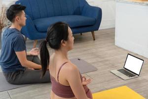 Jeune asiatique sportif couple en train de regarder vidéo Didacticiel entraine toi yoga à Accueil photo