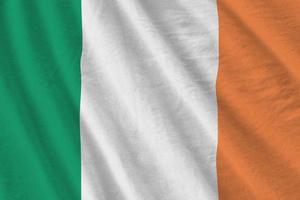 drapeau irlandais avec de grands plis agitant de près sous la lumière du studio à l'intérieur. les symboles et couleurs officiels de la bannière photo