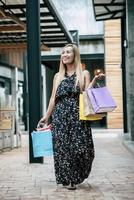 Portrait d'une jeune femme heureuse avec des sacs à provisions marchant dans la rue