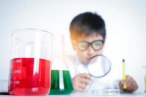 garçon de l'école élémentaire vêtu d'une robe blanche, faisant des expériences scientifiques en laboratoire. concepts de développement de l'éducation des enfants photo