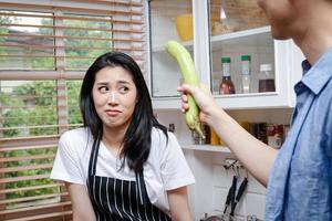 asiatique des couples cuisinier ensemble dans le cuisine à maison. elles ou ils apprécié en jouant et taquineries chaque autre. homme en portant aubergine. cuisine famille concept, départ une couple la vie famille bâtiment photo