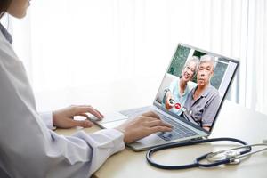une femelle médecin bavardage via en ligne vidéo appels avec un personnes âgées asiatique patient. la communication par en ligne technologie. médecins pouvez examiner les patients par vidéo appels. concept de médical un service photo