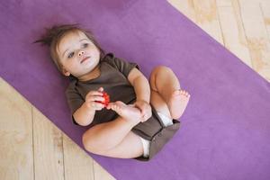 mignonne bébé fille avec massage Balle mensonge sur aptitude tapis photo