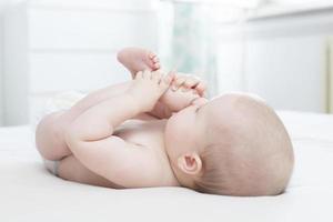 petite fille couchée et tirant sa jambe dans sa bouche photo