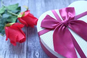 boîte-cadeau en forme de coeur et fleur rose sur fond de bois