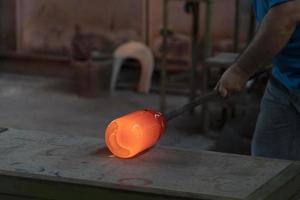 maître verrier tout en travaillant dans l'usine de verre de four de murano venise italie photo