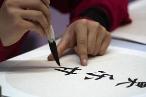Japonais femme l'écriture Nom Charles dans idéogrammes avec brosse photo
