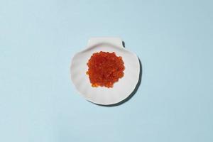 Caviar rouge sur plaque d'orcelaine blanche sur fond bleu photo