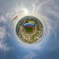 minuscule planète dans ciel avec des nuages surplombant au dessus sur vide stade ou des sports complexe. transformation de sphérique 360 panorama dans abstrait aérien voir. photo