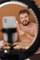 homme vlogging à propos faire en haut et beauté des produits. Masculin tournage une maquillage Didacticiel. gars enseignement faire en haut Didacticiel en utilisant sa téléphone - la diversité et blogueur concept. photo