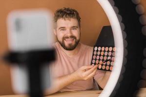 homme vlogging à propos faire en haut et beauté des produits. Masculin tournage une maquillage Didacticiel. gars enseignement faire en haut Didacticiel en utilisant sa téléphone - la diversité et blogueur concept. photo