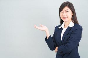 femme asiatique en costume gestes de la paume de la main ouverte avec espace vide photo