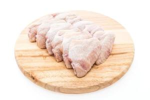 Ailes de poulet frais crus sur une assiette en bois photo