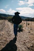 une homme dans une chapeau et une bleu veste des promenades par le désert. photo