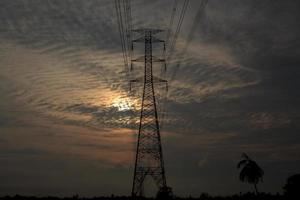 haute tension poteaux sont utilisé à porter électricité pour industriel les plantes et gens à utilisation dans le Les agriculteurs des champs dans le soir. magnifique ciel atmosphère et conçu par électrique ingénieurs. photo