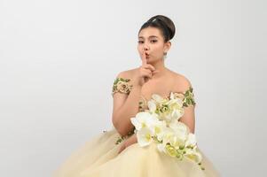 Jeune belle mariée asiatique avec bouquet d'orchidées sur fond blanc photo