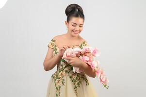 Jeune belle mariée asiatique avec bouquet d'orchidées sur fond blanc photo