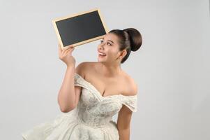 jeune belle mariée asiatique pose avec un tableau blanc à la main photo