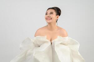 Jeune belle mariée asiatique souriante avec plaisir sur fond blanc photo