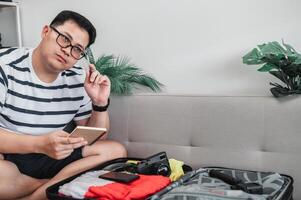 un homme asiatique prépare des vêtements dans des valises photo